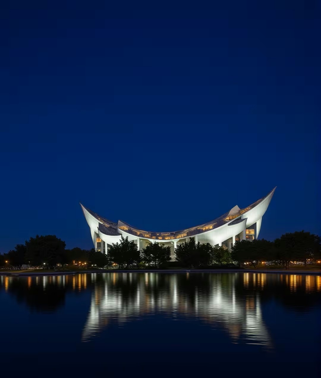 crescent-roofed building glowing above its own reflection at night